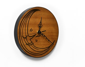 May include: A wooden clock with a black rim and a crescent moon design. The clock hands are black and the clock face is made of wood.