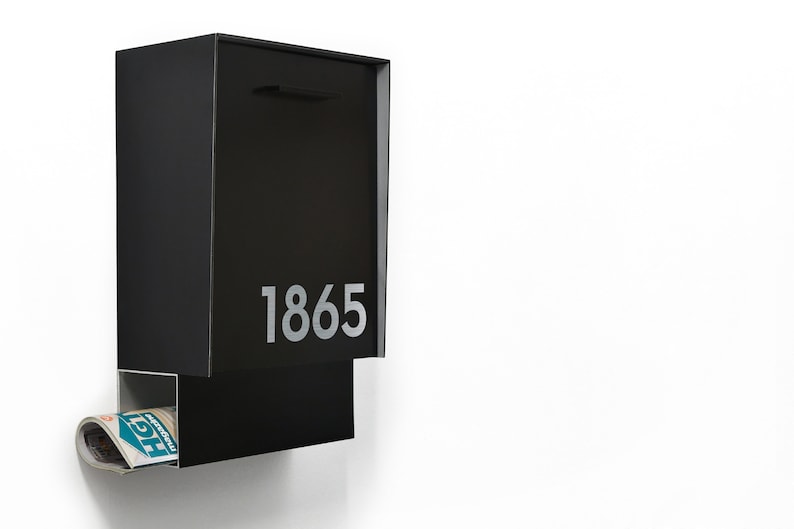May include: A black metal mailbox with a slot for mail and a separate compartment for newspapers. The mailbox has the number 1865 printed on the front.