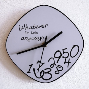 Pode incluir: Um relógio quadrado de cor lilás claro com ponteiros pretos e números pretos. O mostrador do relógio tem o texto "Whatever I'm late anyways".