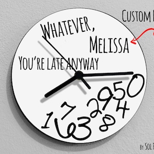 May include: White round clock with black hands and black numbers. The clock face says "Whatever, You're Late Anyway" and has a space for a custom name. The name "Melissa" is written on the clock face. The clock is made by Sol Pixie Dust.