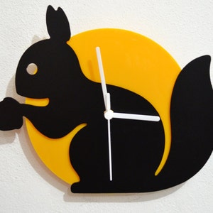 May include: A black silhouette of a squirrel holding a nut, with a yellow circular background and white clock hands.