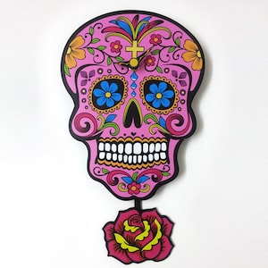 Può includere: Orologio da parete a forma di teschio di zucchero rosa e nero con un design floreale e un pendolo a forma di rosa rossa.