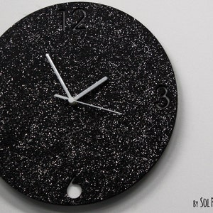May include: A black glitter clock with white hands and numbers. The clock is round and has a diameter of approximately 12 inches.