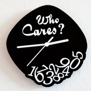 Pode incluir: Um relógio preto com ponteiros e números brancos. O mostrador do relógio tem a forma de um diamante e tem o texto "Who Cares?" escrito nele.