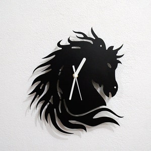 Könnte beinhalten: Schwarze Wanduhr in Form eines Pferdekopfes mit weißen Zeigern. Die Uhr ist aus Metall und hat ein elegantes, modernes Design.