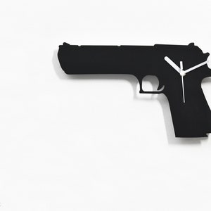 Pode incluir: Silhueta preta de uma pistola com ponteiros de relógio brancos sobre um fundo branco. O mostrador do relógio está no lado da pistola. O texto "By Sol Pixie Dust" está na parte inferior da imagem.