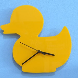 May include: A yellow rubber duck shaped wall clock with black hands.