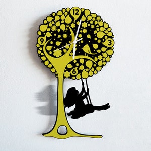 May include: A yellow tree-shaped clock with black details and a girl swinging from a branch. The clock face has black numbers and white hands.
