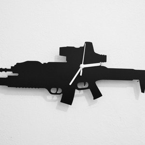 May include: Black silhouette of a rifle with a scope, designed as a wall clock. The clock hands are white.