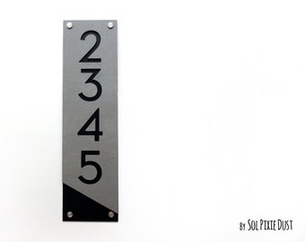 Puede incluir: Un letrero vertical de número de casa con los números 2345 en negro sobre un fondo gris. La parte inferior del letrero es negra.