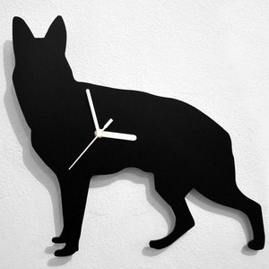 Puede incluir: Silueta negra de un perro pastor alemán con agujas de reloj blancas sobre una pared blanca.