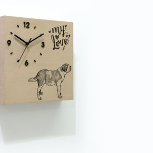 Puede incluir: Un reloj cuadrado de madera con una esfera y agujas negras. La esfera del reloj tiene marcas de números romanos negros. El reloj tiene una ilustración en blanco y negro de un perro y el texto "my love" con corazones.