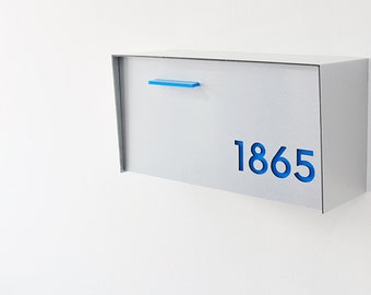 May include: A white metal mailbox with a blue handle and the number 1865 in blue lettering.