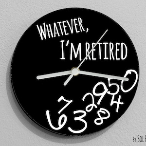 Pode incluir: Relógio redondo preto com texto branco que diz "Whatever, I'm Retired". O mostrador do relógio tem números brancos escritos em um estilo de escrita brincalhão.