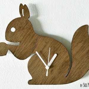 May include: A wooden squirrel-shaped clock with white hands. The clock is stained a dark brown color and has a simple design.