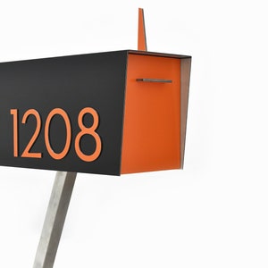Könnte beinhalten: Ein moderner schwarzer und orangefarbener Briefkasten mit einem Ständer aus Edelstahl. Der Briefkasten trägt die Nummer "1208" auf der Vorderseite.