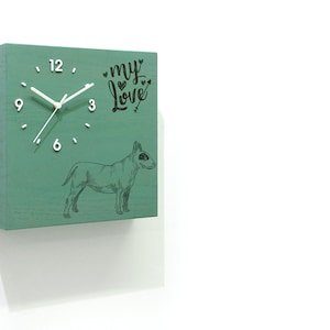 Puede incluir: Un reloj cuadrado verde con agujas blancas y números negros. La esfera del reloj también tiene las palabras "my love" con corazones y una flecha. Una ilustración en blanco y negro de un bull terrier está debajo de la esfera del reloj.