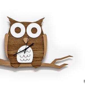 May include: A wooden owl clock with white eyes and a white belly, perched on a branch. The clock has black hands and is made of oak wood. By Sol Pixie Dust.