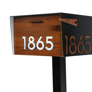 Peut inclure: Une boîte aux lettres noire et en bois avec le numéro 1865 affiché des deux côtés. La boîte aux lettres a une finition en bois et un poteau en métal noir.