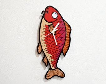 May include: A red, orange and pink fish-shaped wall clock with white clock hands. The fish has a large eye and a small mouth.