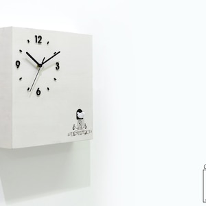 May include: White square cuckoo clock with black hands and numbers. The clock has a small white bird that pops out of the front. The clock has a black and white logo that says "Swiss Made Clock".