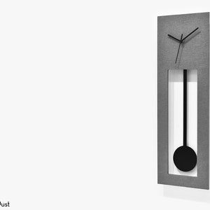 Op de afbeelding: Een zilverkleurige wandklok met een zwarte slinger en zwarte wijzers. De klok heeft een rechthoekige vorm en een geborsteld metalen afwerking.
