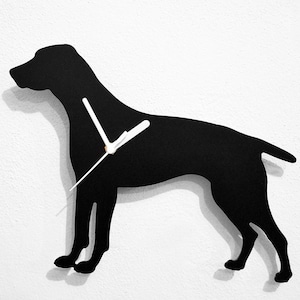 Puede incluir: Silueta negra de un perro con agujas de reloj blancas en una pared blanca.