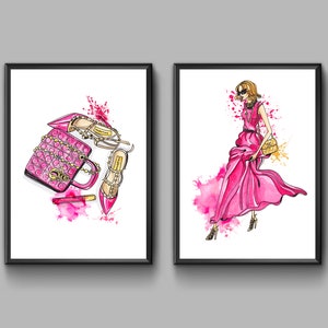 Könnte beinhalten: Zwei gerahmte Illustrationen. Die erste zeigt eine rosafarbene gesteppte Handtasche, rosafarbenen Lippenstift und zwei rosafarbene High-Heel-Schuhe mit goldenen Akzenten. Die zweite Illustration zeigt eine Frau in einem rosafarbenen Kleid mit einer goldenen Handtasche.