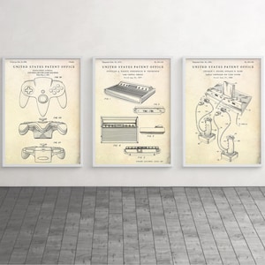 Puede incluir: Tres dibujos de patentes vintage para consolas y mandos de videojuegos. El primer dibujo muestra un mando de Nintendo 64. El segundo dibujo muestra una consola Atari 2600. El tercer dibujo muestra una consola Atari 5200.