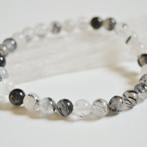 May include: A bracelet made of black tourmaline and clear quartz beads. The beads are round and have a smooth, polished finish.