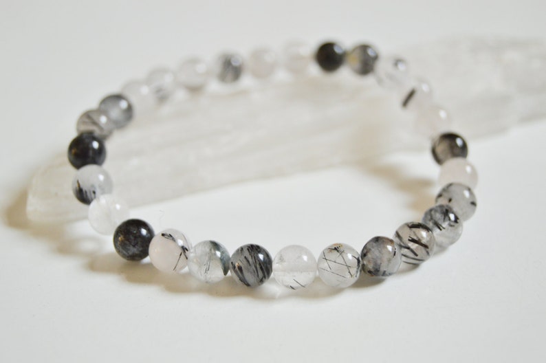May include: A bracelet made of black tourmaline and clear quartz beads. The beads are round and have a smooth, polished finish.