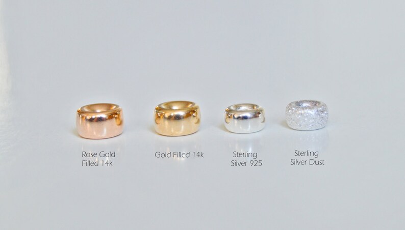 May include: Four different metal beads, each with a different finish. From left to right: rose gold filled 14k, gold filled 14k, sterling silver 925, and sterling silver dust.