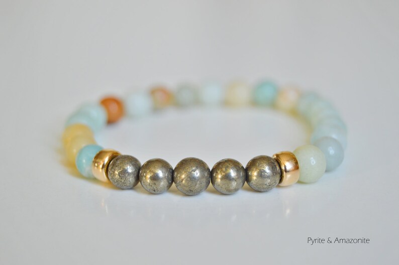 May include: A bracelet made with amazonite and pyrite beads. The bracelet has a gold accent.