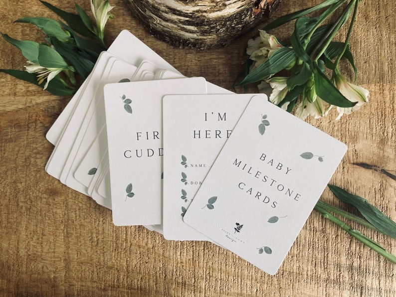 Pode incluir: Um conjunto de cart&otilde;es de marcos para beb&ecirc;s com um design simples que inclui folhas verdes e o texto "Baby Milestone Cards".