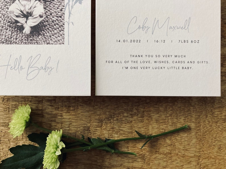 Op de afbeelding: Een witte kaart met de tekst "Hello Baby!" en een zwart-witfoto van een baby. De kaart bevat ook de tekst "Coby Maxwell", "14.01.2022", "16:12", "7LBS 8OZ", "THANK YOU SO VERY MUCH FOR ALL OF THE LOVE. WISHES, CARDS AND GIFTS. I'M ONE VERY LUCKY LITTLE BABY."