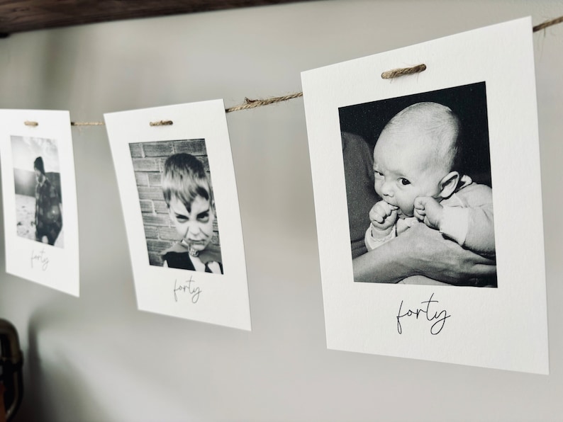 May include: Black and white photos of a baby, a young child, and a teenager, strung together on a twine line with clothespins. Each photo has the word "forty" written below it.