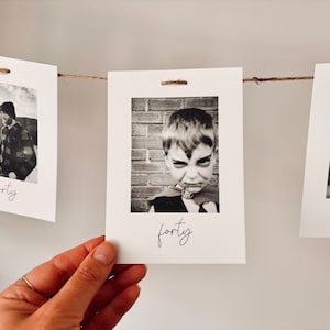 May include: A string of black and white photos with the word "forty" written on each card. The photos show a person in a plaid shirt, a young boy in a costume, and a baby.