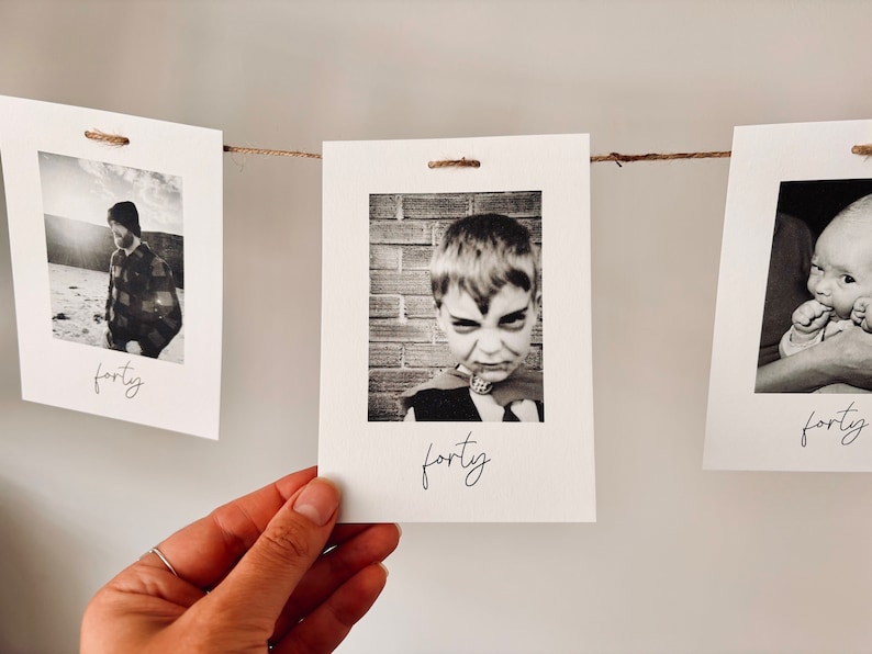 May include: A string of black and white photos with the word "forty" written on each card. The photos show a person in a plaid shirt, a young boy in a costume, and a baby.