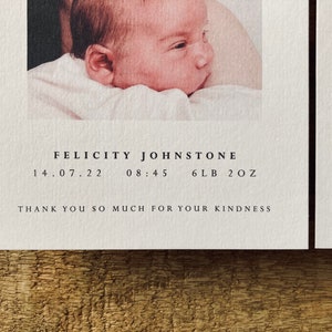 May include: A white card with black text announcing the birth of Felicity Johnstone. The card includes the date of birth, time of birth, and weight of the baby: 14.07.22, 08:45, 6lb 2oz. The text "Thank you so much for your kindness" is also included.
