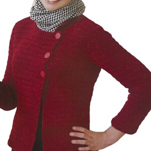 May include: A red crocheted cardigan with a diagonal button closure and three pink buttons. The cardigan has long sleeves and a round neckline.