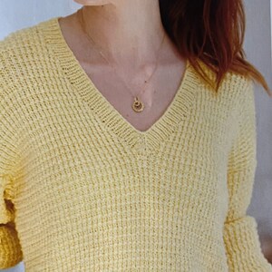 May include: A pale yellow knitted sweater with a v-neck and long sleeves.