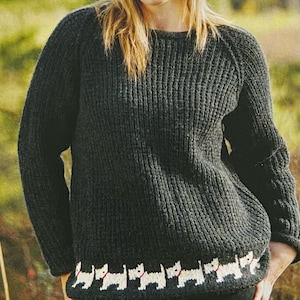 Könnte beinhalten: Ein dunkelgrauer Strickpullover mit einem weißen und roten Stickrand aus kleinen Hunden. Der Pullover hat einen runden Ausschnitt und lange Ärmel.