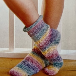 May include: A pair of colorful striped crochet socks with a textured pattern. The socks are made with a variety of colors, including pink, yellow, blue, and green.