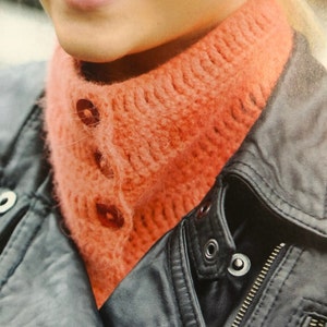 Può includere: Primo piano di un collo a maglia color corallo con tre bottoni. Il collo è indossato sopra una giacca di pelle nera.