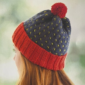 May include: A blue and red knitted hat with a yellow polka dot pattern and a red pompom on top.