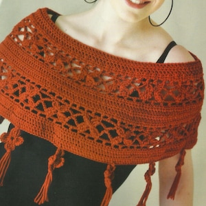 May include: A crocheted shawl with a lacy pattern and tassels. The shawl is a deep orange color.