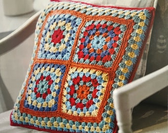 May include: A colorful crocheted pillow with a geometric pattern of squares. The pillow is made with red, orange, yellow, blue, and green yarn.