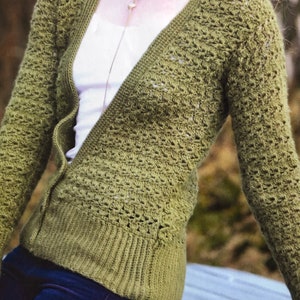 May include: A green crocheted cardigan with a v-neck and long sleeves. The cardigan has a button closure and a delicate crocheted pattern.