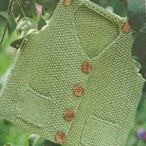 May include: A green knitted vest with a button closure and two pockets. The vest is hanging on a branch.