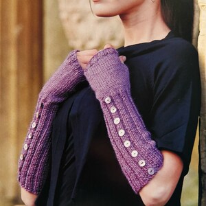 May include: A pair of purple fingerless gloves with button accents. The gloves are knitted and have a ribbed texture.